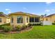 View of the backyard featuring a sunroom, well-maintained lawn, and landscape at 17425 Eagle Trace Dr, Brooksville, FL 34604