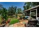 Landscaped backyard featuring mature trees, patio with seating area, and screened-in porch at 1942 Ashland Dr, Clearwater, FL 33763