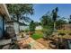 View of the landscaped backyard featuring mature trees, grass, patio with seating area and privacy fence at 1942 Ashland Dr, Clearwater, FL 33763