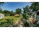 Spacious backyard featuring mature trees, lush green grass, with a screened-in porch and garden at 1942 Ashland Dr, Clearwater, FL 33763