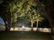 Night shot of a well-lit backyard with a white fence and mature trees at 2004 Chickwood Ct, Tampa, FL 33618