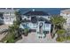 Aerial view of a light blue waterfront home with palm trees, a dark roof, and a driveway made of patterned pavers at 2111 Alexis Ct, Tarpon Springs, FL 34689