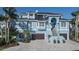 Gorgeous light blue home with a two-car garage, brick driveway, lush landscaping, and stylish staircase to the entry at 2111 Alexis Ct, Tarpon Springs, FL 34689