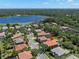 Aerial view of a lakeside community with houses with backyard pools and mature landscaping surrounded by mature trees at 2671 Lakebreeze S Ln, Clearwater, FL 33759