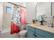 Stylish bathroom with a blue vanity, round mirror, and decorative shower curtain at 2671 Lakebreeze S Ln, Clearwater, FL 33759