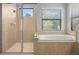 Well-lit bathroom featuring a walk-in shower, bathtub, and windows at 2671 Lakebreeze S Ln, Clearwater, FL 33759