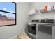 Bright laundry room featuring stainless steel washer and dryer, plus a window for natural light at 2671 Lakebreeze S Ln, Clearwater, FL 33759