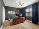 Home office featuring a large wooden desk, guitar, and a modern ceiling fan at 2671 Lakebreeze S Ln, Clearwater, FL 33759