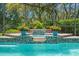 Relaxing in-ground pool with decorative water feature, surrounded by lush tropical plants in a screened enclosure at 2671 Lakebreeze S Ln, Clearwater, FL 33759