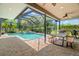 Screened-in pool area with a table, grill and lush landscaping, perfect for outdoor entertaining at 2671 Lakebreeze S Ln, Clearwater, FL 33759