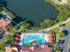 Aerial view of a community pool with cabanas, surrounded by lush landscaping and a lake at 2741 Via Cipriani # 931A, Clearwater, FL 33764