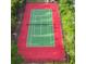 Aerial view of a vibrant, well-maintained tennis court with a red and green surface, surrounded by lush greenery at 2741 Via Cipriani # 931A, Clearwater, FL 33764