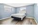 Comfortable bedroom features a cozy bed, hardwood floors and natural light through two windows at 3654 Warbler Dr, New Port Richey, FL 34652