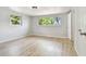Spacious bedroom featuring two windows, neutral paint, modern ceiling fan, and updated wood flooring at 5810 8Th Ave, New Port Richey, FL 34652