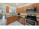 Well-lit kitchen with stainless steel appliances, wooden cabinets, and a view to the living area at 903 Pinellas Bayway S # 308, Tierra Verde, FL 33715