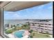 Beautiful pool view showing the pool, Intracoastal Waterway, manicured lawn and lush palm trees under a clear blue sky at 100 Bluff View Dr # 510A, Belleair Bluffs, FL 33770