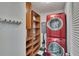 Bright laundry room with stacked red washer and dryer, shelving, and checkered floors at 100 Bluff View Dr # 510A, Belleair Bluffs, FL 33770