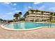 Beautiful in-ground pool with nearby building, lush palm trees, and lounge chairs at 100 Bluff View Dr # 510A, Belleair Bluffs, FL 33770