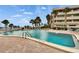 Well-maintained in-ground pool with nearby building, lush palm trees, and lounge chairs at 100 Bluff View Dr # 510A, Belleair Bluffs, FL 33770