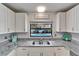 Bright kitchen showcasing white cabinets, granite countertops, and a view of the pool through the window at 1213 Callista Ave, Valrico, FL 33596