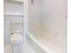 White-tiled bathroom featuring a bright toilet, tub, and shelving unit at 12405 3Rd E St # 306, Treasure Island, FL 33706