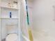 Well-lit bathroom featuring a white toilet, bath tub, shower curtain, and storage shelves at 12405 3Rd E St # 306, Treasure Island, FL 33706