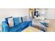A bright, comfortable living room area with a blue sectional couch and an eat-in kitchen at 12405 3Rd E St # 306, Treasure Island, FL 33706