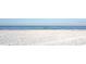 Pristine white sandy beach meeting the clear blue ocean water on a sunny day at 1500 Sunset Rd # C7, Tarpon Springs, FL 34689