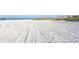 Expansive white sandy beach with tire tracks leading to the ocean and distant buildings at 1500 Sunset Rd # C7, Tarpon Springs, FL 34689