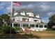 Elegant two-story home with a covered porch, manicured lawn, and American flag at 1500 Sunset Rd # C7, Tarpon Springs, FL 34689