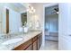 Bathroom vanity with granite counters, dual sinks, and a view of the bedroom at 15305 Fishhawk Preserve Dr, Lithia, FL 33547
