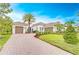 Beautiful home boasting a three-car garage, clay tile roof, and a meticulously designed front yard with palm trees at 15305 Fishhawk Preserve Dr, Lithia, FL 33547
