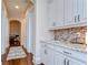 Hallway with white cabinetry, granite countertops, mosaic backsplash, and hardwood flooring at 15305 Fishhawk Preserve Dr, Lithia, FL 33547
