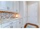 A well-appointed pantry featuring white cabinetry, granite counters, and a stylish tile backsplash at 15305 Fishhawk Preserve Dr, Lithia, FL 33547
