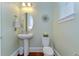 Stylish powder room featuring a pedestal sink, decorative mirror, and modern fixtures with lovely neutral paint color at 15305 Fishhawk Preserve Dr, Lithia, FL 33547