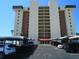 Condo building exterior showcasing balconies, covered parking, and landscaping under a clear blue sky at 15400 Gulf Blvd # 502, Madeira Beach, FL 33708