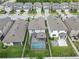 Aerial view of a home with a pool, fenced yard, and an outdoor firepit in a residential area at 19926 Stone Pine Cir, Lutz, FL 33558