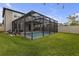Spacious backyard with green grass, white fence, mature trees, and a screened-in pool area at 19926 Stone Pine Cir, Lutz, FL 33558