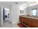 Bathroom features a double vanity with granite counters and wood cabinets with a view to the bedroom at 19926 Stone Pine Cir, Lutz, FL 33558