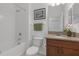 Clean bathroom with tub and shower combo, wooden vanity and granite top, and white tile flooring at 19926 Stone Pine Cir, Lutz, FL 33558