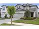 Two-story gray home featuring a two-car garage and neatly maintained landscaping with a paved driveway at 19926 Stone Pine Cir, Lutz, FL 33558