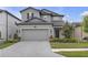 Two-story gray home featuring a two-car garage, manicured landscaping, and a neatly paved driveway at 19926 Stone Pine Cir, Lutz, FL 33558