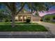 Inviting single-story home featuring a well-manicured lawn, tidy landscaping and welcoming front porch at dusk at 20537 Lace Cascade Rd, Land O Lakes, FL 34637