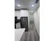 Modern kitchen with stainless steel appliances, white cabinets, and an adjacent hallway with light wood flooring at 2108 E 22Nd Ave # 1, Tampa, FL 33605