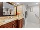 Bathroom vanity featuring granite countertop, wood cabinets, large mirror, and adjacent shower with decorative tile at 220 Belleview Blvd # 104, Belleair, FL 33756