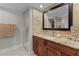 Tastefully updated bathroom with granite countertop, wood cabinets, and neutral stone tiling at 220 Belleview Blvd # 104, Belleair, FL 33756