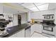 Cozy kitchen featuring white cabinets, stainless steel appliances, and stone countertops at 220 Belleview Blvd # 104, Belleair, FL 33756