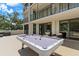 Spacious outdoor patio with pool table, seating, and sliding glass doors to luxurious condo at 220 Belleview Blvd # 104, Belleair, FL 33756