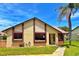 Well-maintained home with tan siding, brown trim, and a lush green lawn complemented by a mature palm tree at 2459 Bay Berry Dr, Clearwater, FL 33763