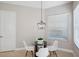 Bright dining area featuring a modern chandelier, a glass-topped table, and views of the exterior through the window at 2495 Oakwood Preserve Dr, Wesley Chapel, FL 33543